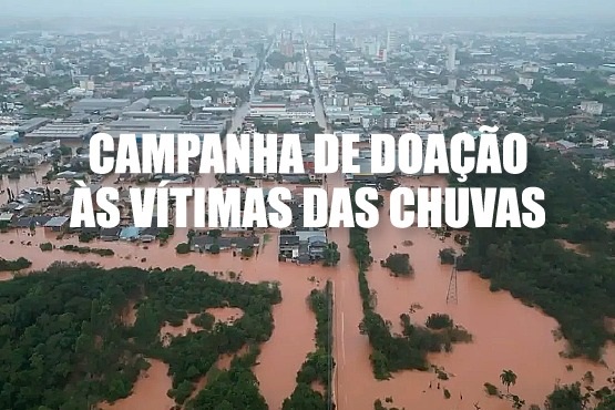Imagem aérea das cidades afetadas pelas enchentes no estado do Rio Grande do Sul. Frase "campanha de doação ás vitimas das chuvas" sobrepondo a imagem.