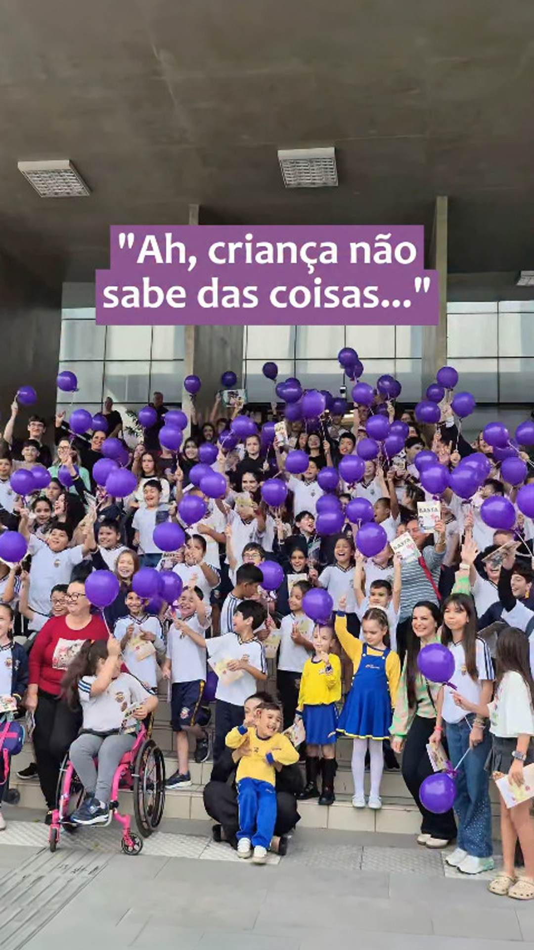 Grupo de estudantes crianças em visita ao TJSC, segurando balões na cor roxa