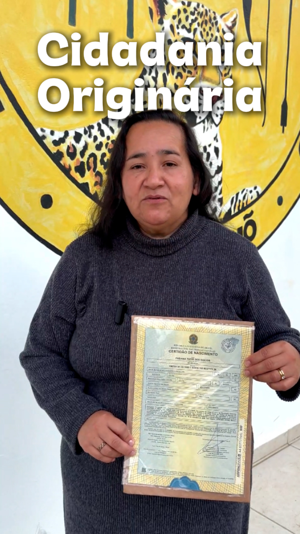 Imagem de uma mulher indígena segurando uma certidão de nascimento que consta a sua etnia.