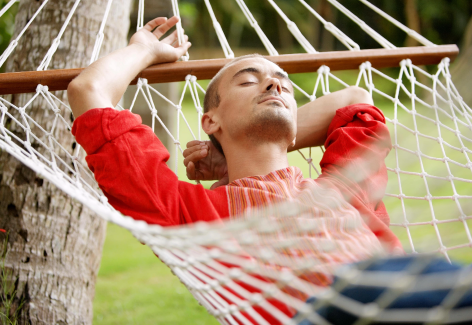 Imagem de um homem descansando numa rede.