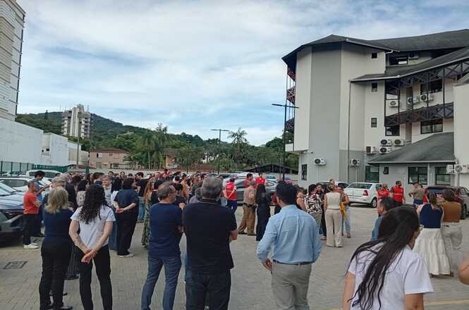 Dezenas de pessoas, entre eles brigadistas, servidores e magistrados, de pé no estacionamento do Fórum, aguardam conclusão do simulado