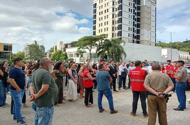 Dezenas de pessoas, entre eles brigadistas, servidores e magistrados, de pé no estacionamento do Fórum, recebem orientação de bombeiros