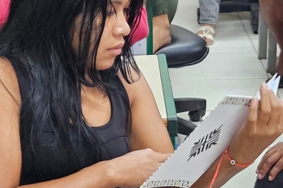 Mulher lendo cartilha sobre a Lei Maria da Penha em guarani