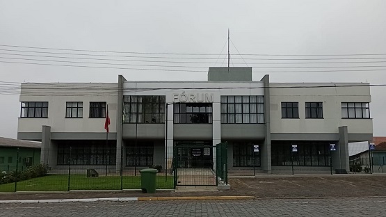 Faixada do Fórum de Itaiópolis, com gramado e bandeiras em frente ao prédio. 
