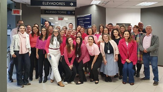 Servidores posam para foto usando roupas cor de rosa. 
