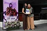Foto da desembargadora Hildemar Meneguzzi de Carvalho entregando a premiação a uma das vencedoras