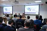 Foto geral do evento com foco na mesa de palestrantes 