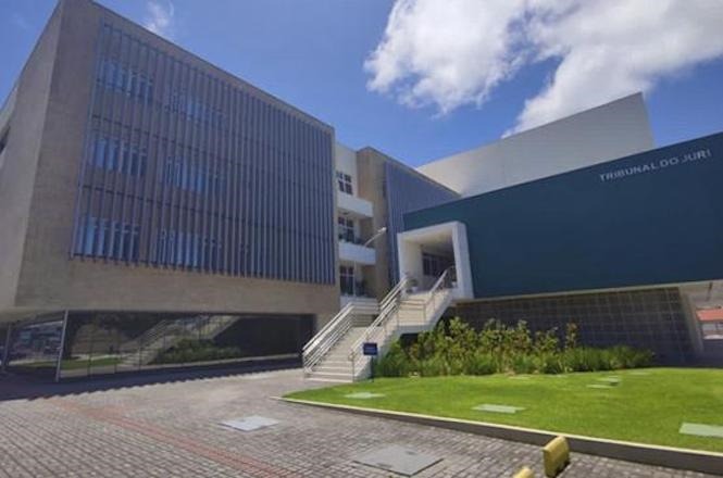 Foto horizontal: fachada do Fórum da comarca de Navegantes, com arquitetura contemporânea, acesso por escadaria, área ajardinada e edifício do Tribunal do Júri em destaque à direita.