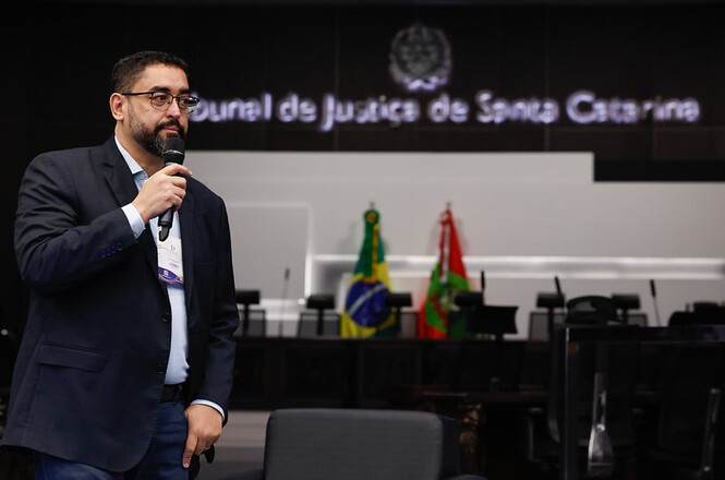 Foto horizontal: participante utiliza microfone durante palestra realizada no Tribunal de Justiça de Santa Catarina, em atividade de capacitação voltada a magistrados e servidores.