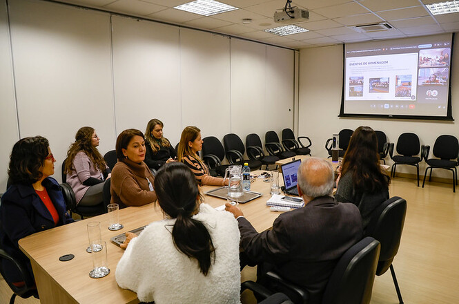 Foto horizontal: servidores participam de reunião por videoconferência durante apresentação de resultados e ações institucionais.
