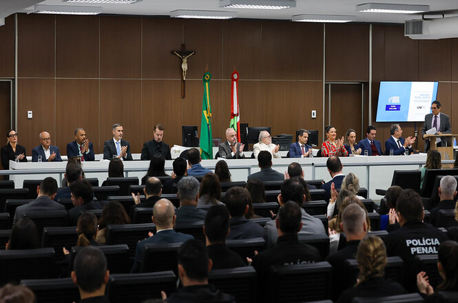 Foto horizontal: Mesa de autoridades prestigia o lançamento da Central de Regulação de Vagas do Sistema Prisional e do Emprega LaB, com público presente no auditório.