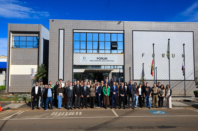 Foto horizontal: autoridades e servidores posam diante do Fórum Prof. Ithamar Gama Lobo D’Eça, sob céu azul.