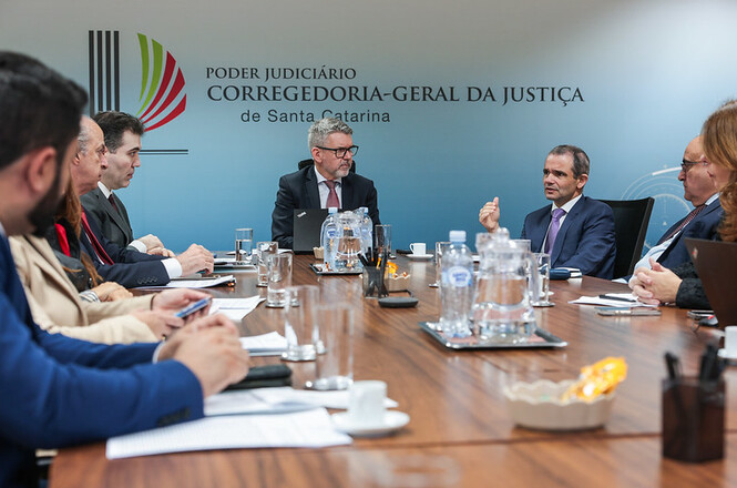 Foto horizontal: autoridade de terno azul e gravata roxa gesticula durante reunião na Corregedoria-Geral da Justiça.