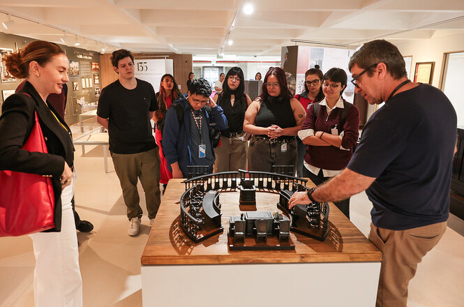 Foto horizontal: visitantes observam maquete histórica do plenário durante visita guiada à exposição dos 135 anos do TJSC.