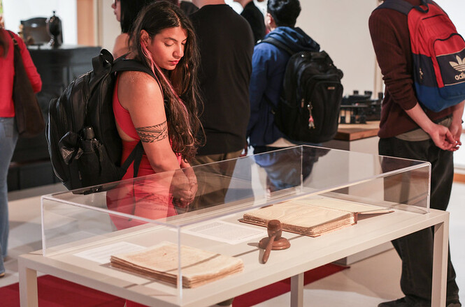 Foto horizontal: visitante observa documentos históricos e um malhete expostos em vitrine durante mostra dos 135 anos do TJSC.