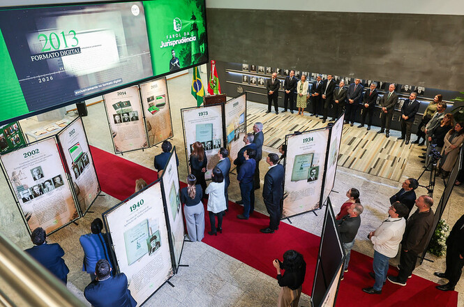 Foto horizontal: autoridades e convidados visitam a exposição Farol da Jurisprudência, com painéis que apresentam a trajetória histórica do TJSC.