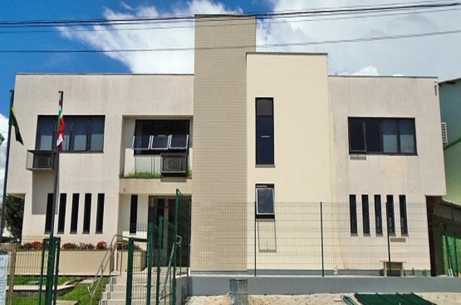 Foto horizontal: fachada do Fórum da Comarca de Bom Retiro, com bandeiras, escadaria e grades na área externa.