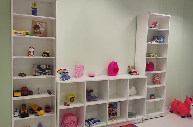Foto horizontal: estantes com brinquedos, livros e materiais lúdicos compõem espaço de acolhimento infantil preparado para atender crianças no fórum.