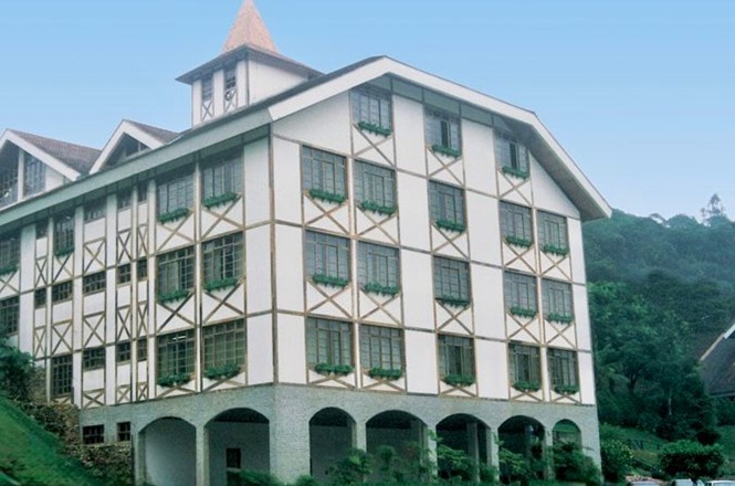 Foto horizontal: fachada da comarca de Brusque com arquitetura enxaimel, prédio em destaque em área verde, clima institucional.