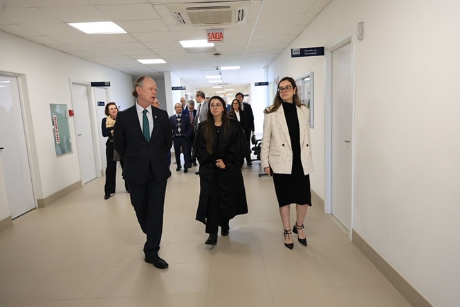 Foto horizontal: presidente do TJSC, desembargador Rubens Schulz, caminha pelo corredor do Fórum acompanhado por duas mulheres, durante visita institucional.