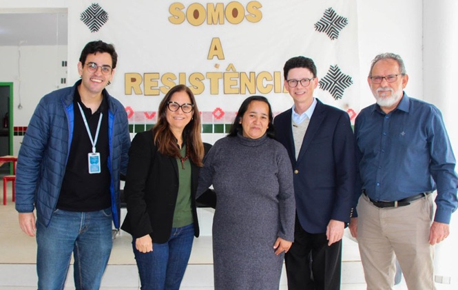 Rosane Portella Wolff, de preto e verde, posando com grupo em espaço comunitário interno, ação de cidadania, registrando encontro em preto, verde, azul e branco