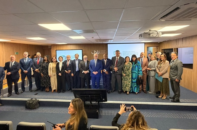 Foto horizontal: grupo de magistrados e representantes do Judiciário posa no auditório do CNJ após encontro institucional.
