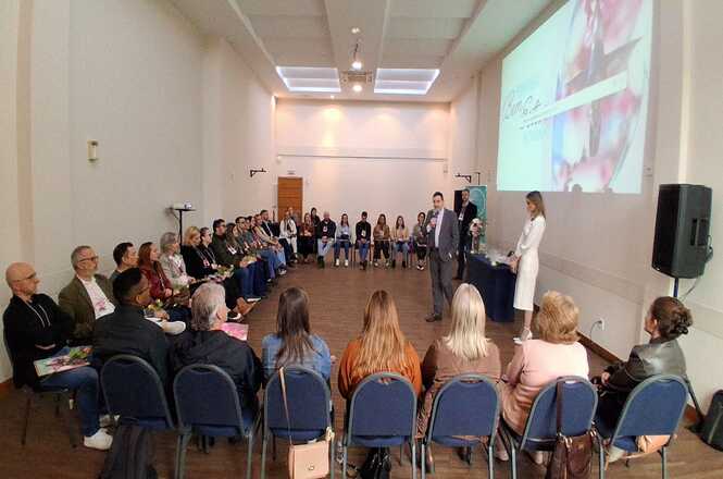 Foto horizontal: atividade do programa Bem-Estar no Trabalho com participantes em círculo, facilitador ao centro conduz dinâmica, ambiente amplo, clima de integração.