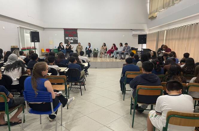Imagem horizontal mostra estudantes acompanhando roda de conversa sobre bullying e respeito em ambiente escolar.