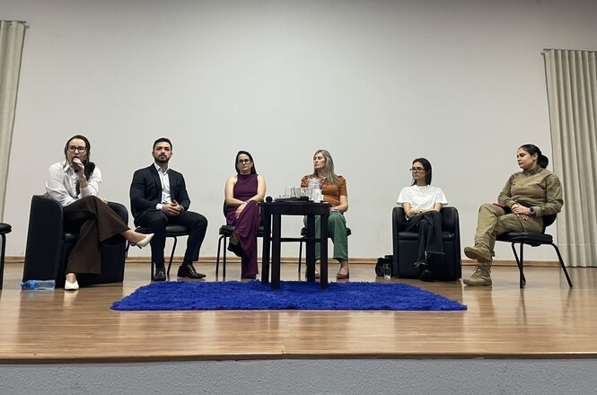 Imagem horizontal mostra autoridades em roda de conversa sobre bullying e respeito, durante atividade educativa.