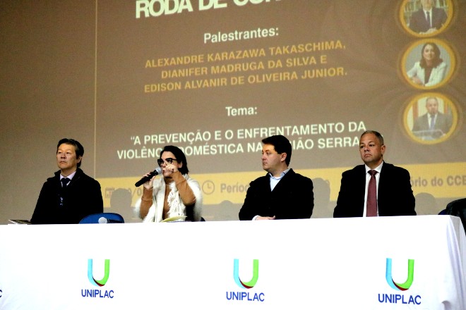 Foto Horizontal: Dianifer Madruga da Silva fala ao microfone durante roda de conversa sobre enfrentamento da violência doméstica. 