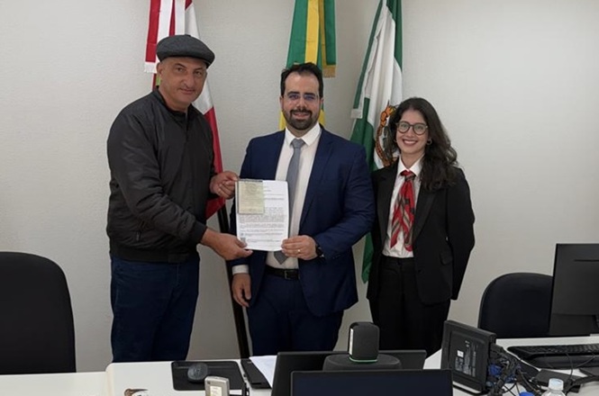 Representante recebe documento durante entrega oficial de veículo em Presidente Getúlio, ao lado de autoridades.