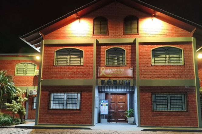 Foto horizontal: fachada do Fórum iluminada à noite exibe faixa do Setembro Amarelo em campanha de valorização da vida.