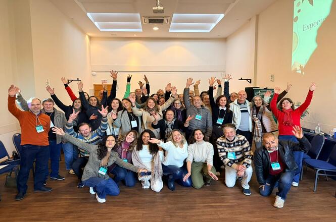Foto horizontal: participante fala ao microfone durante atividade do Programa de Preparação para a Aposentadoria, acompanhada por facilitadores.