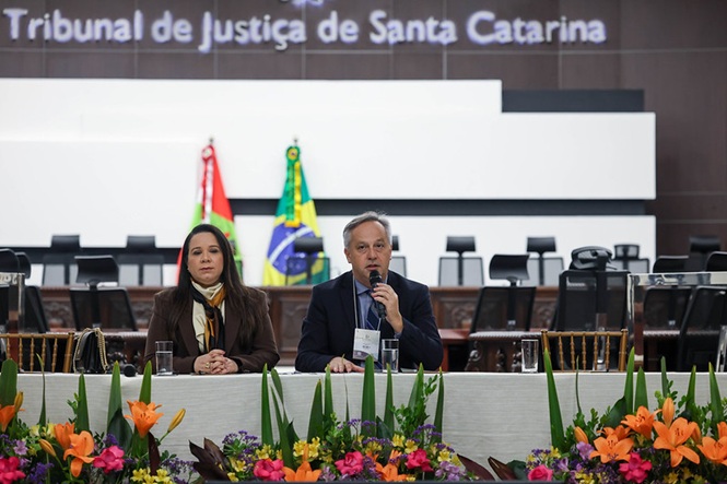 Autoridades compõem mesa no TJSC durante evento do Programa Indira, com fala ao microfone e debate institucional em destaque