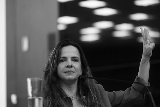 Lili de Grammont fala no TJSC com gesto firme, expressão séria e foco em superação da violência e esperança
