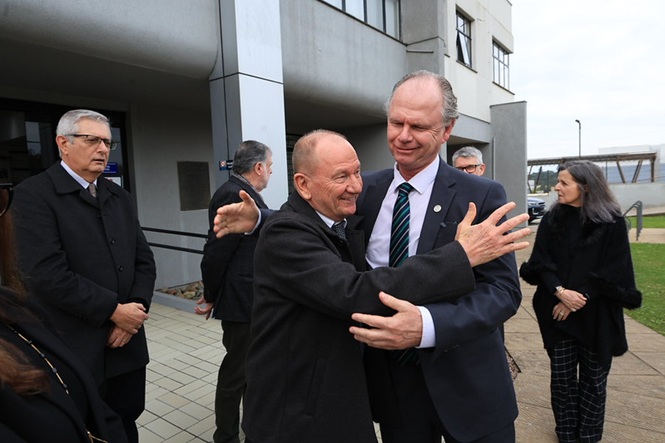 Foto horizontal: presidente do TJSC, desembargador Rubens Schulz, recebe abraço de autoridade durante encontro em frente ao Fórum.