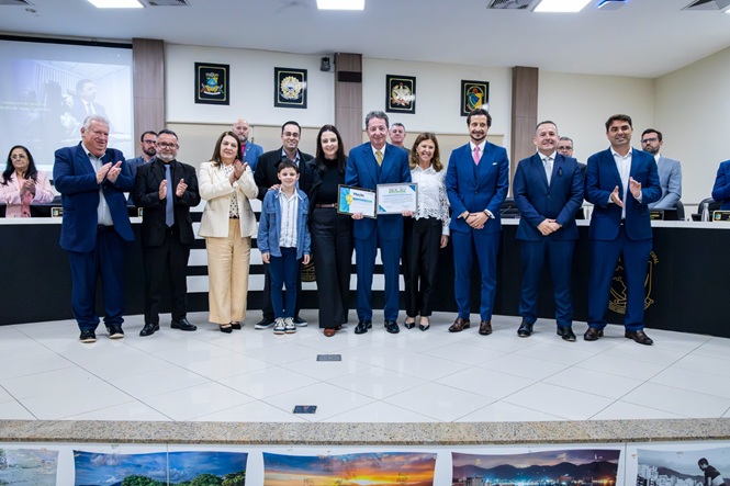 Foto horizontal: desembargador Ricardo Roesler, ao centro, exibe certificados e posa com familiares, magistrados e autoridades durante homenagem no plenário.