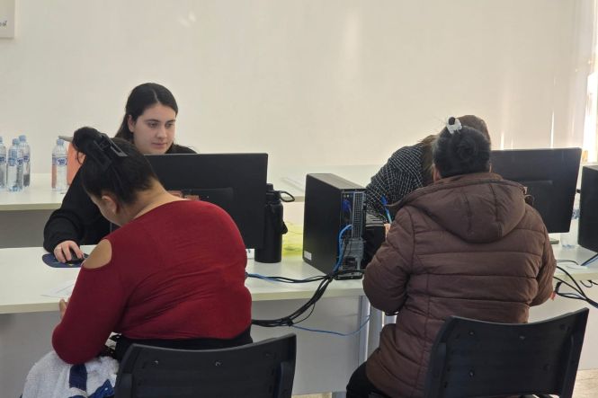 Foto horizontal: servidoras atendem cidadãos em computadores durante ação do programa Justiça Até Você, em Criciúma.