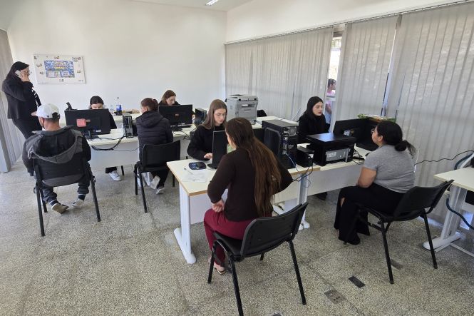 Foto horizontal: servidores atendem cidadãos em computadores durante ação do programa Justiça Até Você, em Criciúma.