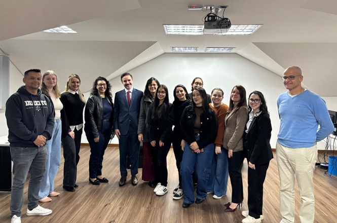 Foto horizontal: grupo de participantes posa para foto durante visita institucional a uma unidade do Poder Judiciário.