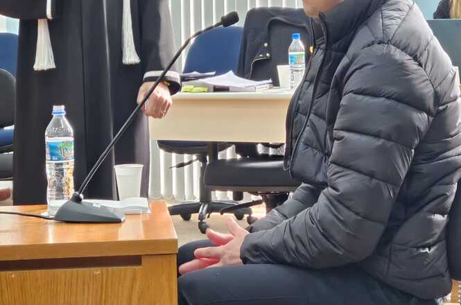 Foto horizontal: homem presta depoimento durante sessão do Tribunal do Júri, sentado diante do microfone em plenário judicial.