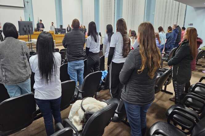 Foto horizontal: familiares, estudantes e comunidade acompanham sessão do Tribunal do Júri, em pé, durante julgamento realizado em plenário.
