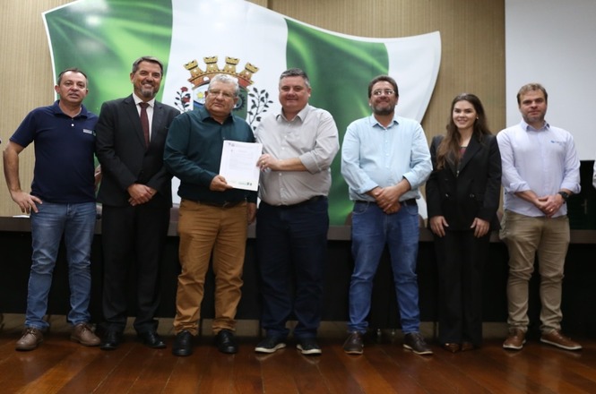 Representante recebe título de propriedade durante entrega de documentos do Programa Lar Legal.