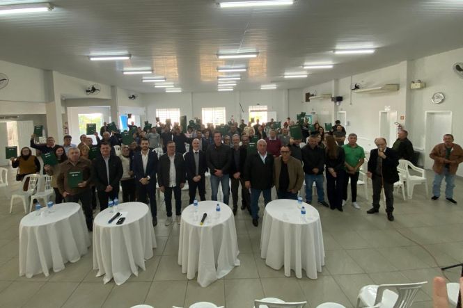 Foto horizontal: participantes do Programa Lar Legal Rural reúnem-se em cerimônia de entrega de documentos de regularização fundiária, com autoridades e beneficiários reunidos no salão do evento.