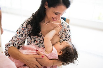 Foto horizontal: mulher amamenta bebê no colo, em imagem que retrata cuidado e aleitamento materno.