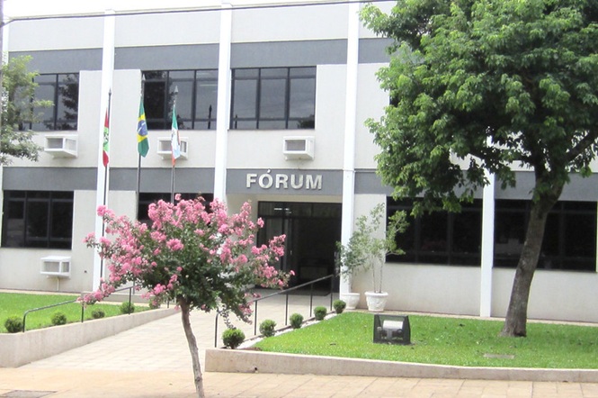 Foto horizontal: fachada do fórum de Mondaí, prédio institucional com área verde em destaque, clima de acesso à Justiça.