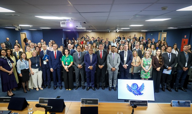 Foto horizontal: autoridades e participantes reunidos para registro coletivo durante evento em auditório.