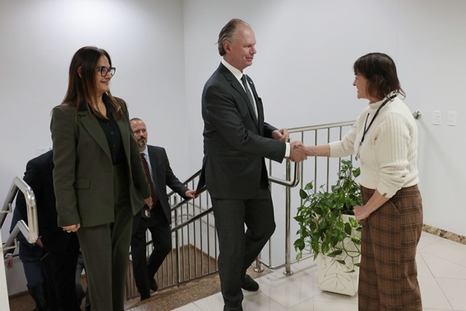 Foto horizontal: o desembargador Rubens Schulz cumprimenta servidora em ambiente institucional, gesto de acolhimento e proximidade.