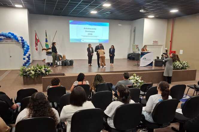 Foto horizontal: participantes acompanham cerimônia de entrega de certificados do programa Novos Caminhos, em auditório de Brusque.