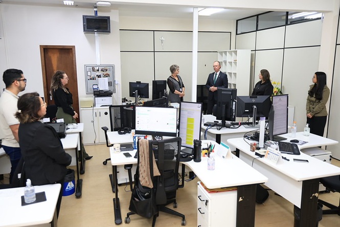 Foto horizontal: presidente do TJSC, desembargador Rubens Schulz, conversa com servidores reunidos em setor de trabalho durante visita ao Fórum.